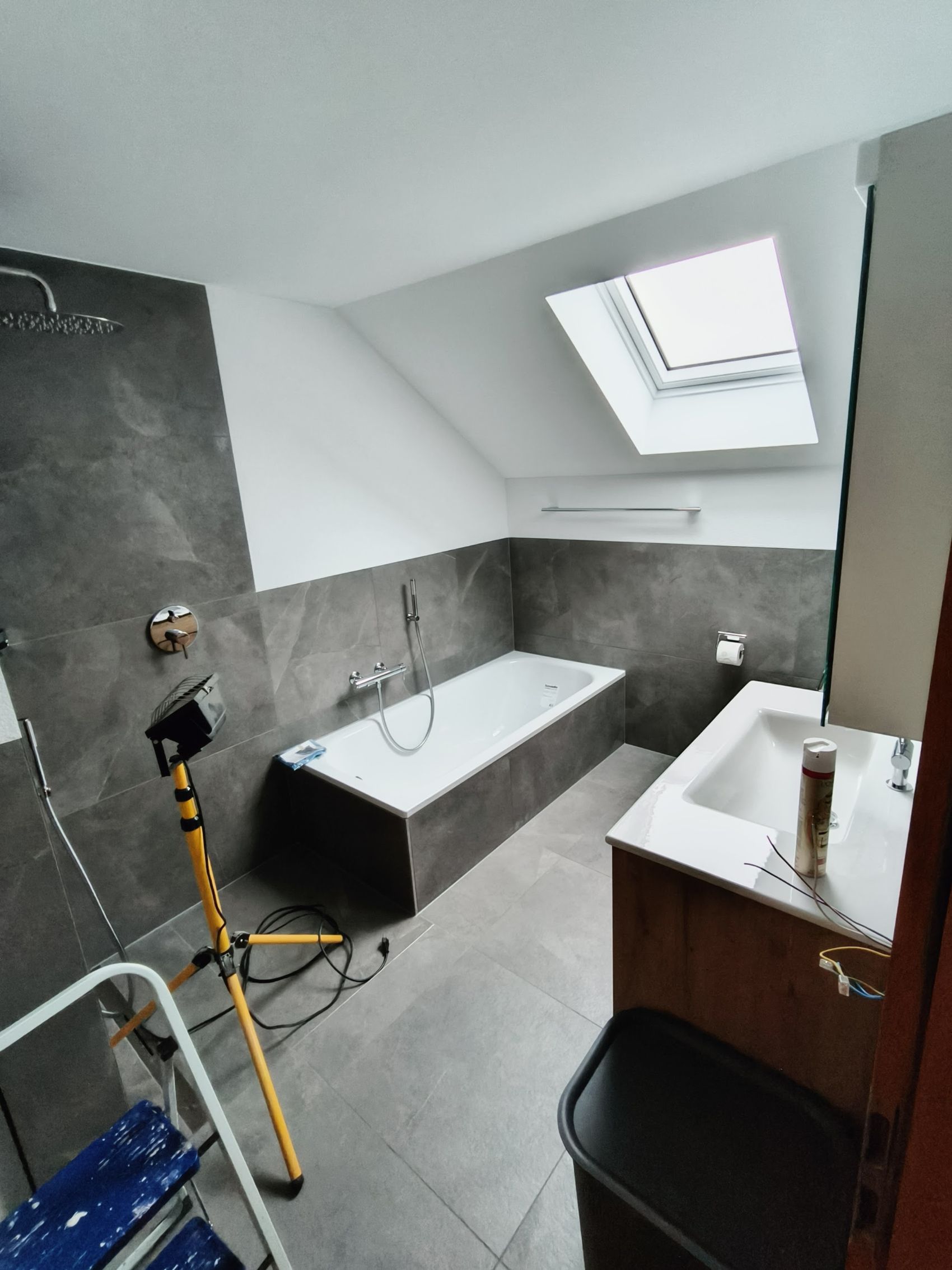 Dachbad mit dunklen Wandplatten und Badewanne