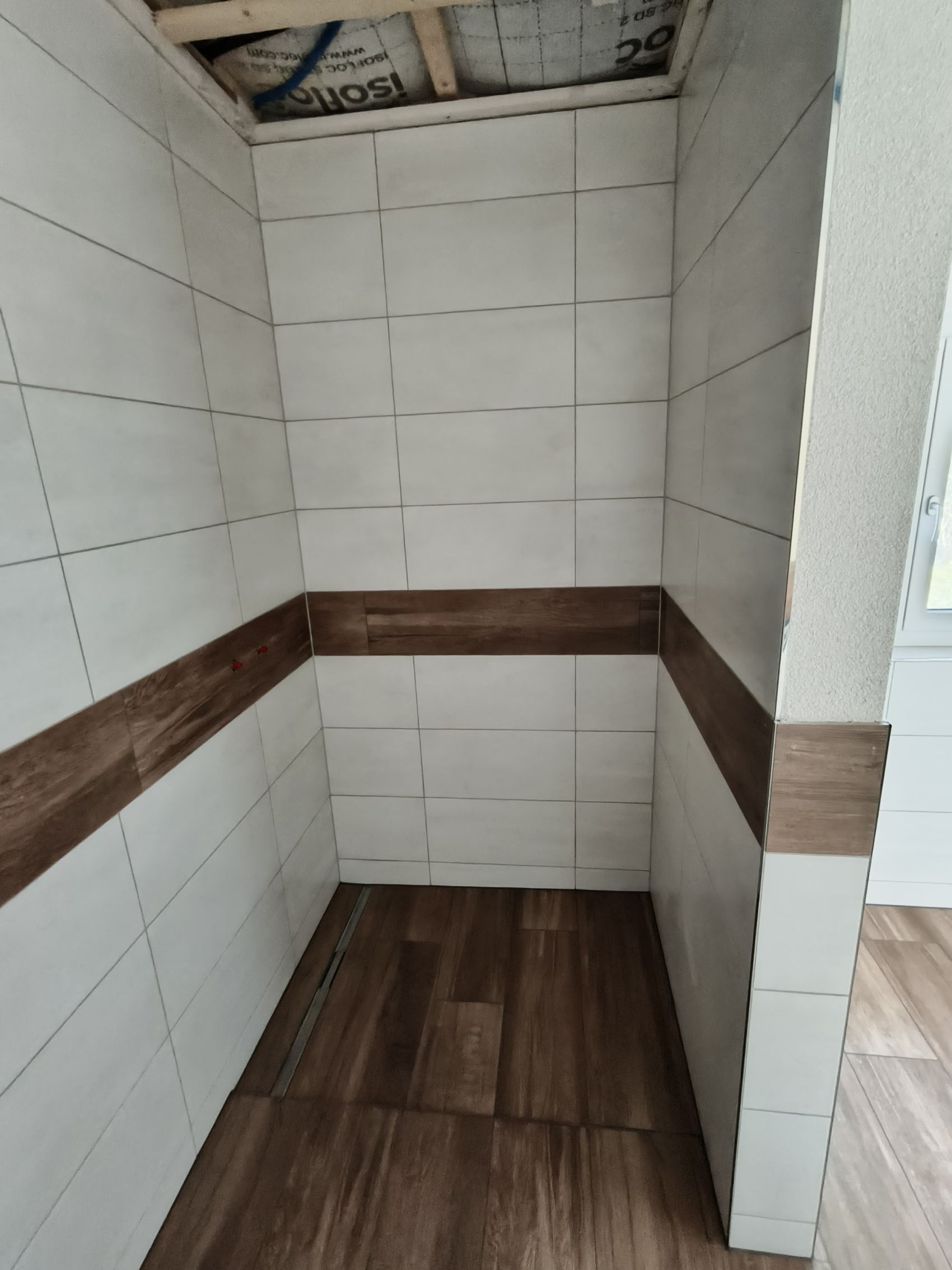 Dusche mit weissen Wandplatten und Holzoptik-Band