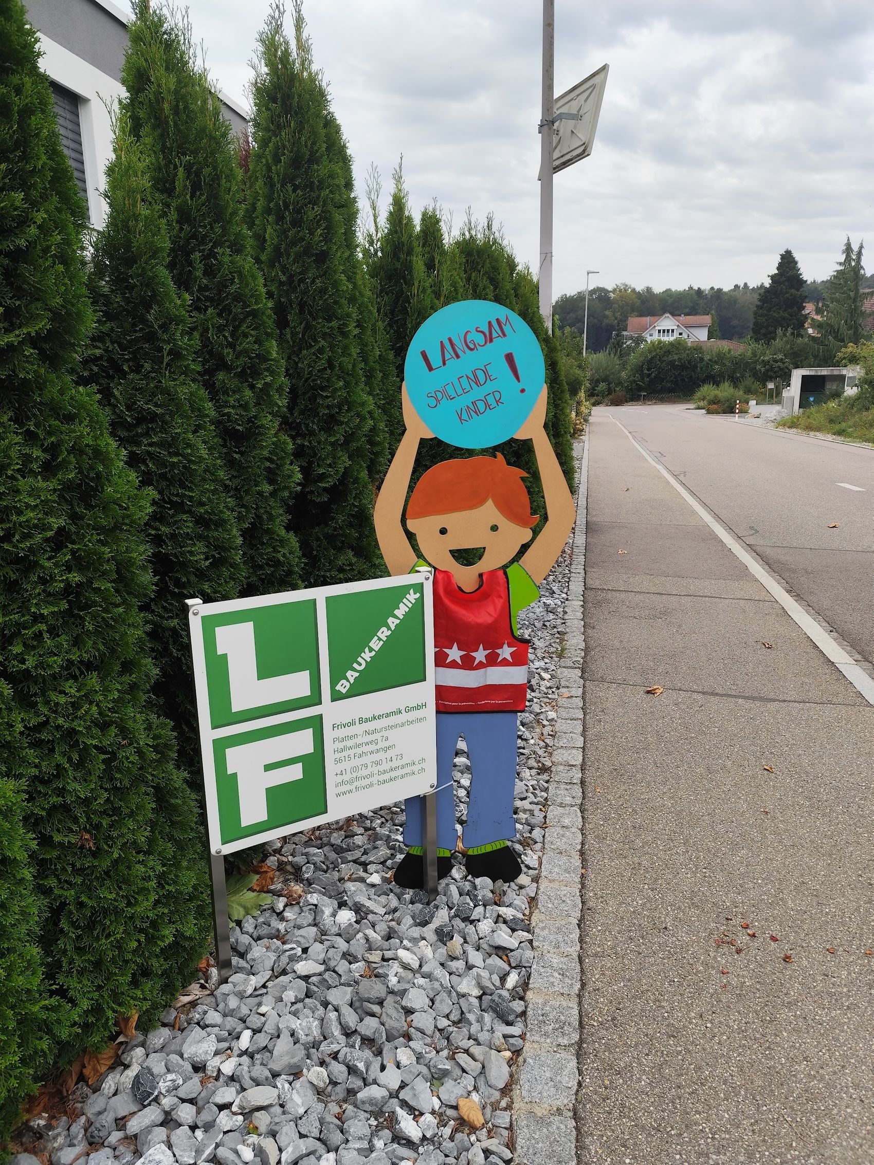 Baustellenschild von Frivoli Baukeramik vor einer Thujahecke