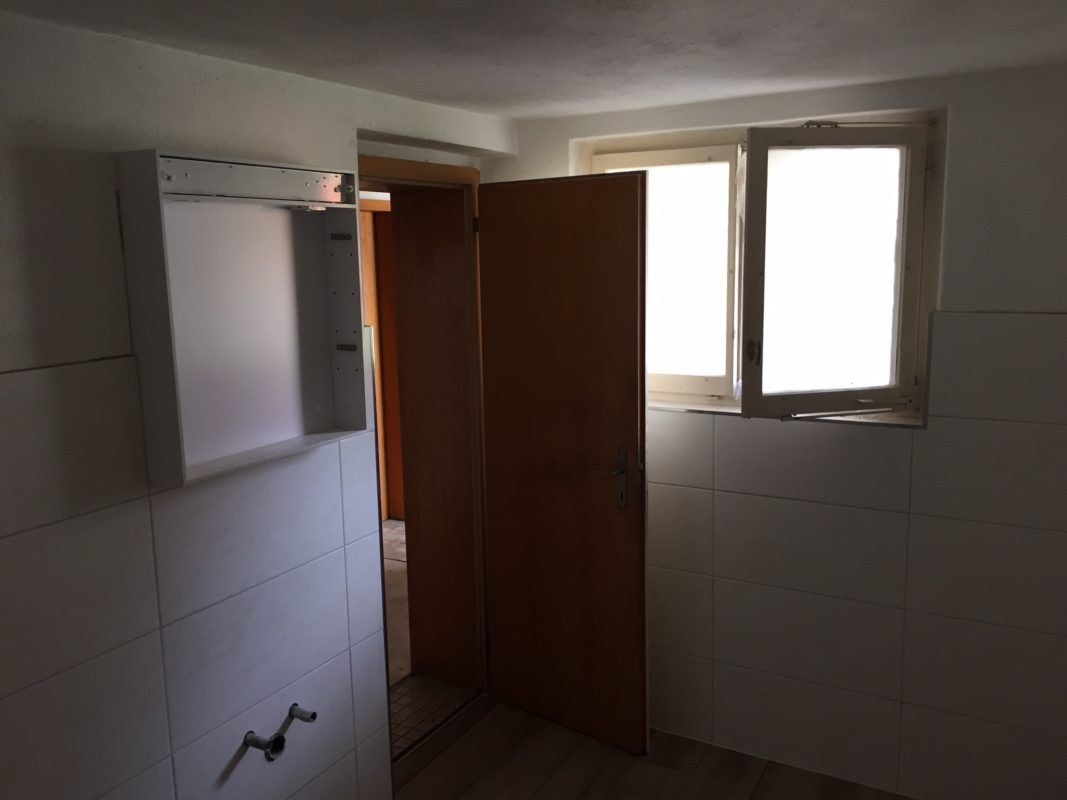 Bad mit weissen Wandplatten und Spiegelschrank