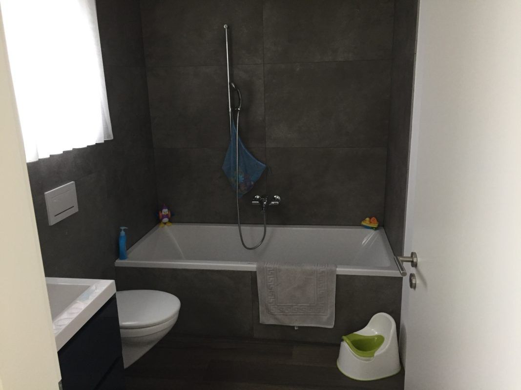 Badezimmer mit dunklen Wandplatten und Wanne